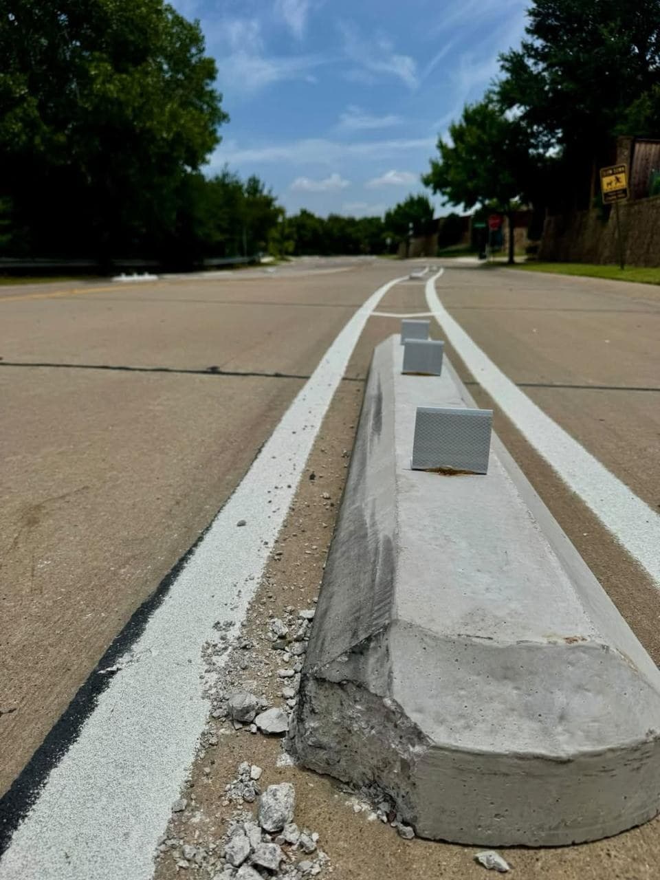 Close view of a damaged concrete traffic-calming barrier on King Arthur Boulevard