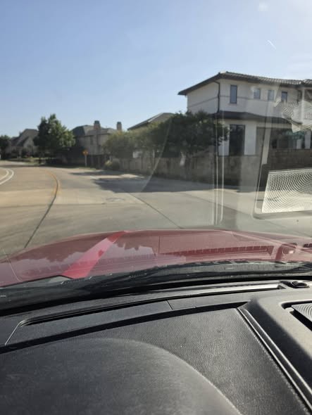 Driver-eye view showing a concrete bump-out blending with sunlit pavement and adjacent shadows